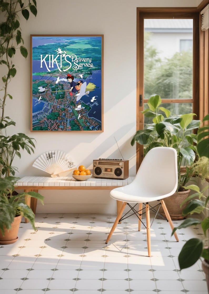 K&ouml;nnte beinhalten: Ein gerahmtes Poster von "Kikis kleiner Lieferservice" h&auml;ngt &uuml;ber einer Bank mit einem F&auml;cher und einer Schale mit Orangen. Ein Vintage-Radio steht auf der Bank. Ein wei&szlig;er Stuhl mit Holzbeinen steht neben der Bank. Topfpflanzen umgeben die Szene.