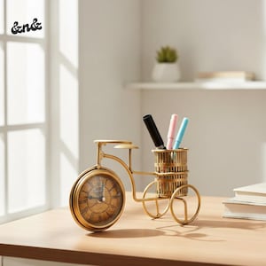 May include: A gold-colored bicycle-shaped desk organizer with a clock face on the front wheel and a pen holder in the back. The clock has Roman numerals. Three pens are in the pen holder. The desk organizer is on a wooden surface.
