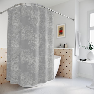 May include: A gray shower curtain with a repeating pattern of white, organic shapes. The curtain hangs from a curved, silver-colored shower rod. The bathroom has a white tub, a small table, and a framed artwork.