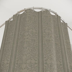 May include: A shower curtain with a floral pattern and vertical stripes in shades of gray and green. The curtain hangs from a curved, silver-colored shower rod. The fabric has a textured appearance.