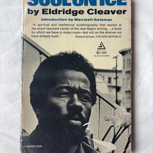 May include: Vintage paperback book titled "Soul on Ice" by Eldridge Cleaver. The cover features a black and white portrait of a man with a beard. The title is in blue, and the author's name is in white. The book is a Delta publication.