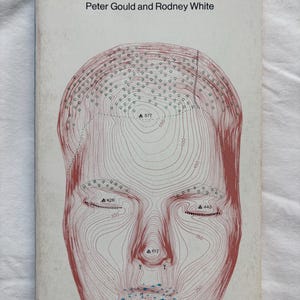 May include: A paperback book titled Mental Maps by Peter Gould and Rodney White. The white cover features a red line drawing of a human face rendered as a topographic map with elevation numbers, contour lines, and small blue symbols.