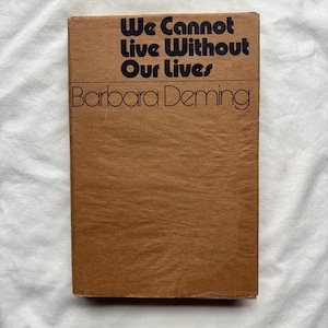 May include: A rectangular book with a tan, textured paper cover. The title "We Cannot Live Without Our Lives" is printed in bold, black, sans-serif font at the top, followed by the author name "Barbara Deming" in a thinner, black font.