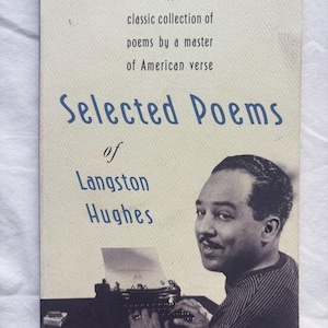 Może przedstawiać: Książka w miękkiej oprawie zatytułowana Selected Poems of Langston Hughes, klasyczny zbi&oacute;r wierszy mistrza amerykańskiej poezji. Okładka zawiera czarno-białe zdjęcie Langstona Hughesa piszącego na maszynie przy ciemnym biurku.