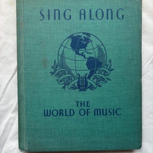 May include: A vintage teal book titled "Sing Along" with the subtitle "The World of Music." The cover features a globe graphic with a lyre and laurel wreath. The book has a textured cover.