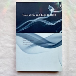 May include: A softcover book titled Causation and Explanation, edited by Joseph Keim Campbell, Michael O'Rourke, and Harry Silverstein. The cover features a dark blue top section and a light blue bottom section, both with white smoke patterns.