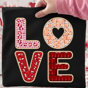 May include: Black pillowcase with the word "LOVE" spelled out in decorative letters. The letters are embellished with pink, red, and peach-colored gems and a gold border. The "O" features a heart-shaped cutout.