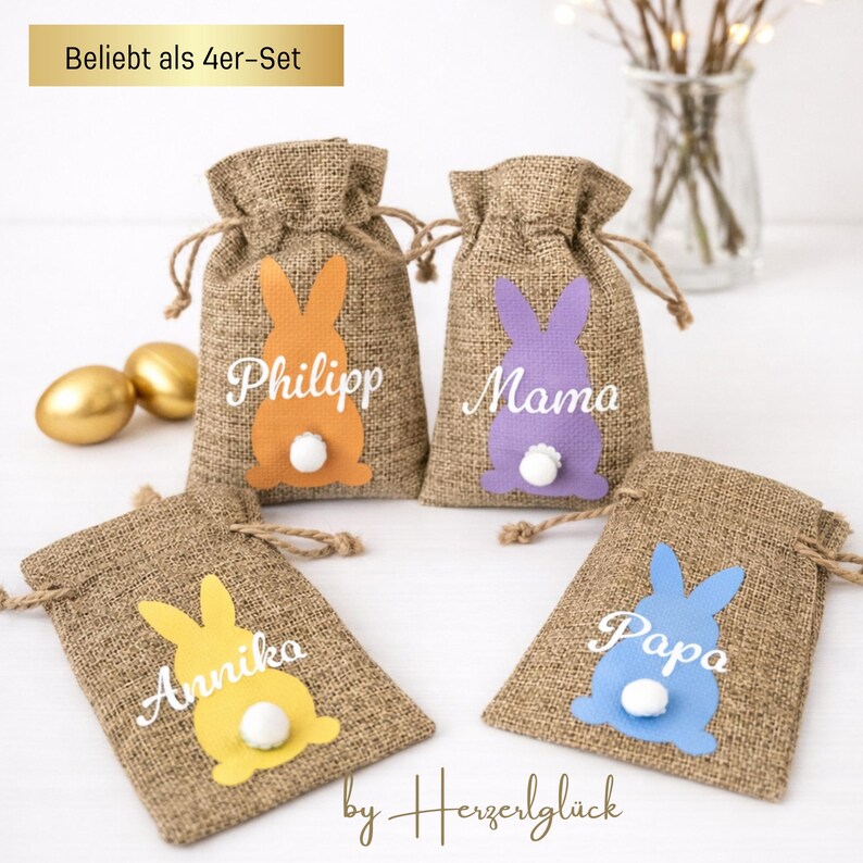 May include: Four burlap Easter gift bags with bunny silhouettes in orange, purple, yellow, and blue. Each bag has a white pom-pom tail and a name: Philipp, Mama, Annika, and Papa. The text "Beliebt als 4er-Set" is at the top.