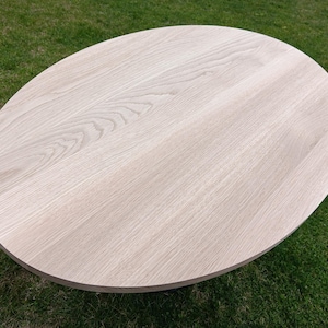 May include: A light wood oval table top with a wood grain pattern.