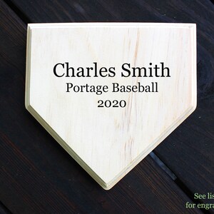 May include: A wooden home plate with the text "Charles Smith Portage Baseball 2020" engraved on it.
