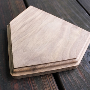 May include: A wooden home decor item shaped like a baseball diamond. The wood is a light brown color and has a natural grain pattern.