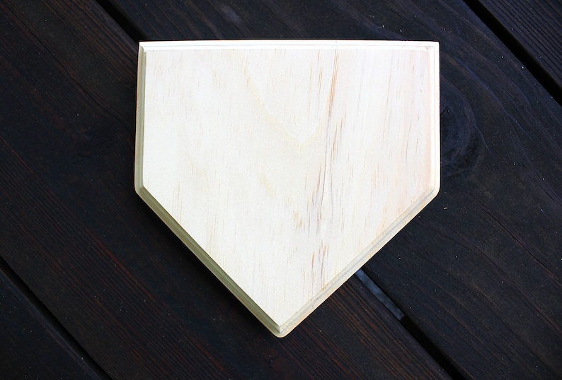 May include: A plain, unfinished wooden home plate, perfect for decorating or crafting.