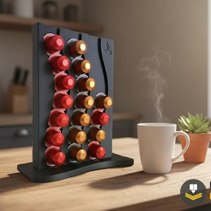 May include: A black coffee pod holder with a curved design, holding red and gold coffee pods. A white mug with steam rising from it and a small potted succulent sit on a wooden table.