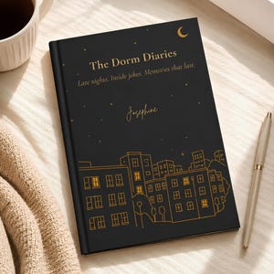 May include: A black hardcover journal featuring gold line art of a city skyline at night with stars and a crescent moon. The cover displays the text "The Dorm Diaries", "Late nights. Inside jokes. Memories that last.", and the name "Josephine".