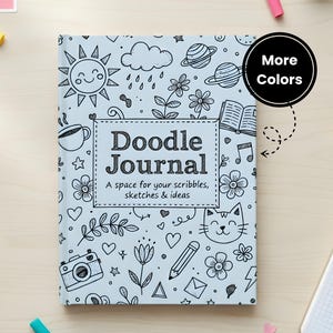May include: A light blue Doodle Journal with a whimsical design of doodles, including a sun, flowers, and a cat. The journal cover features the text "Doodle Journal" and "A space for your scribbles, sketches & ideas."