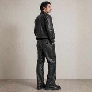 May include: A black leather jacket and matching pants. The jacket has a classic collar and a straight hem. The pants are straight-legged and have a relaxed fit. The outfit is worn with black boots. The text "Outer Store" is visible in the background.