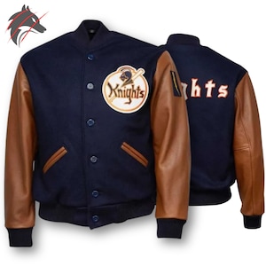 May include: A navy blue varsity jacket with brown leather sleeves. The jacket features a Knights logo patch on the chest and the word "Knights" embroidered on the back. It has a button-up front and two front pockets.