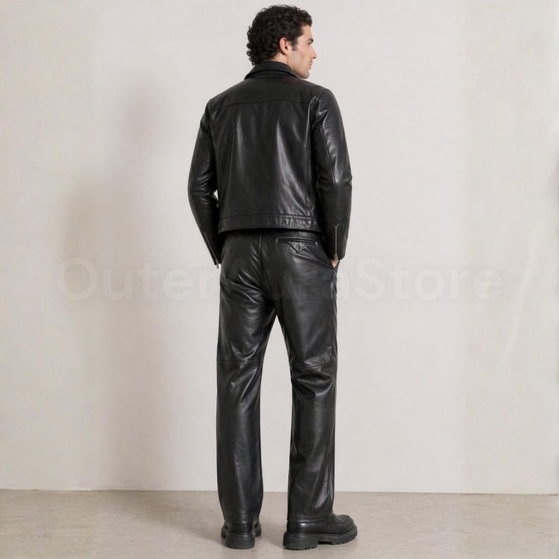 May include: A black leather jacket and matching pants. The jacket has a collar and a zipper closure. The pants are straight-legged. The person is wearing black boots. The outfit is a classic, timeless style.