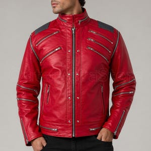 Könnte beinhalten: Eine leuchtend rote Lederjacke mit mehreren silbernen Reißverschlüssen und einem Stehkragen. Die Jacke hat ein gestepptes Design an den Schultern und einen zentralen Reißverschluss. Die Ärmel haben mehrere Reißverschlüsse.