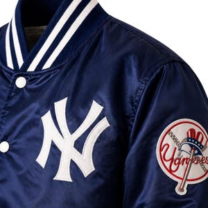 May include: Navy blue satin baseball jacket with white accents. Features the New York Yankees logo on the chest and a team patch on the sleeve. The jacket has a button-up front and a striped collar.