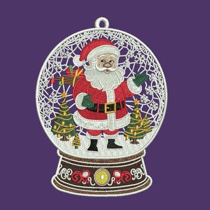 May include: Embroidered Christmas ornament featuring Santa Claus inside a snow globe. Santa wears a red suit, black boots, and green gloves. The snow globe has a white filigree design with two Christmas trees and a brown base. The background is purple.
