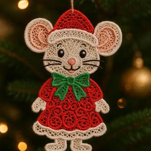 Può includere: Un ornamento natalizio a forma di topo, realizzato in pizzo rosso, bianco e verde. Il topo indossa un cappello e un vestito da Babbo Natale, con un fiocco verde. L'ornamento è appeso a un filo sottile marrone, su uno sfondo sfocato di albero di Natale.