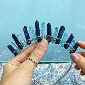 Può includere: Una fascia per capelli argentata ornata da una fila di punte di cristallo blu in varie tonalità. I cristalli sono fissati con filo d'argento, creando un accessorio unico ed elegante. I cristalli variano dal blu chiaro all'indaco scuro.