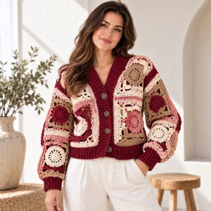 May include: A long-sleeve crochet cardigan featuring a patchwork design of circular and square motifs in shades of burgundy, cream, and tan. The garment has a deep V-neckline, a ribbed burgundy button-front placket, and ribbed cuffs.