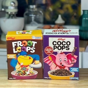 Op de afbeelding: Twee Kellogg's ontbijtgranen dozen: Froot Loops en Coco Pops. De Froot Loops doos is bruin met een blauwe aap en kleurrijke ontbijtgranen. De Coco Pops doos is paars met een roze olifant en chocolade ontbijtgranen. Beide dozen zijn 500g.