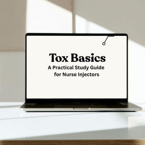 May include: A laptop displaying the text "Tox Basics: A Practical Study Guide for Nurse Injectors." The laptop is open on a white surface, with a light-colored wall in the background. The screen is bright and the text is in a bold, clear font.