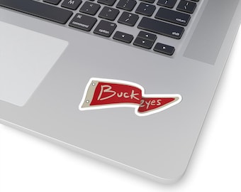 May include: A red and white sticker with the word "Buckeyes" in a banner design. The sticker is on a laptop, with the keyboard visible in the background.