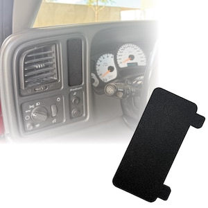 May include: A black textured automotive dashboard panel with a rectangular shape and a small tab. The panel is shown next to a car's dashboard, including air vents, light controls, and gauges. The word "Podium" is visible on the dashboard.