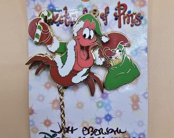 Pin oficial vintage de Disney que muestra a Sebastián el cangrejo con temática navideña de La Sirenita.