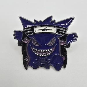 May include: A purple enamel pin featuring a cartoon ghost character with a white headband. The pin has a black outline and a white-toothed grin. The design is a fusion of two popular anime and video game franchises.