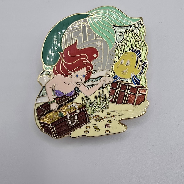 Vintage official Disney pin that shows Ariel and Flounder from The Little Mermaid next to treasures from a sunken ship