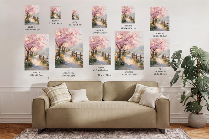 May include: Watercolor painting of a path lined with a wooden fence and cherry blossom trees. Various sizes are displayed, including 12x36 inches, 8x10 inches, and 16.5x23.5 inches. The artwork is displayed above a sofa.