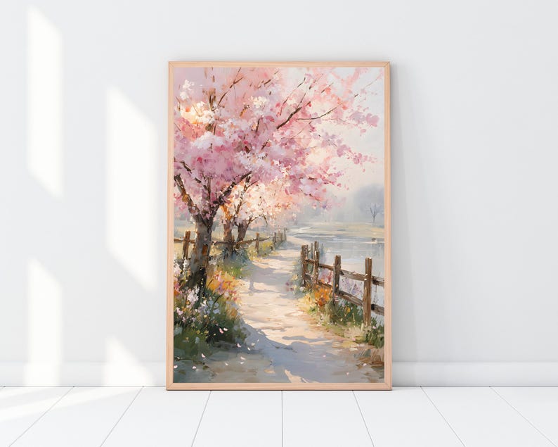 May include: A framed watercolor painting of a path lined with cherry blossom trees. The trees have pink and white blossoms. A wooden fence runs along the path, and a body of water is visible in the background. The painting is in a light wood frame.