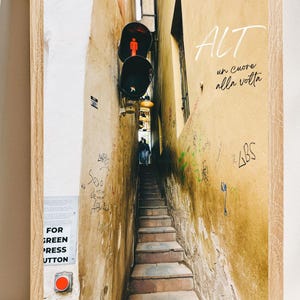 Può includere: Fotografia incorniciata di un vicolo stretto con scale che conducono verso l'alto. Le pareti sono vecchie e coperte di graffiti. Un semaforo con un segnale pedonale rosso è visibile. Il testo nell'immagine recita "ALT un cuore alla volta".