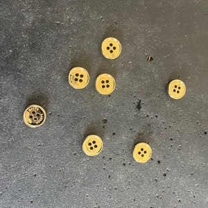 May include: Eight gold-coloured buttons with a raised design and the text "MARTIN CARDINAL" on each button.