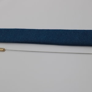 May include: A gold-colored cleaning tool with a long, thin wire and a small ring at the end. The tool is in a blue fabric case with a velcro closure.