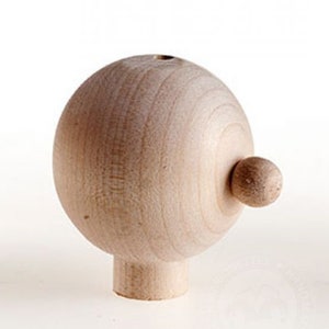 Könnte beinhalten: Ein Holzpuppenkopf mit einer runden, glatten Oberfläche und einem kleinen Knopf an der Seite. Der Kopf ist unbemalt und hat eine natürliche Holzfarbe.