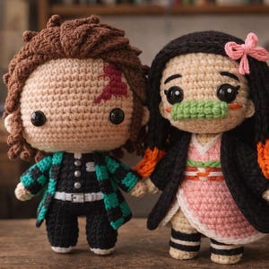 May include: Two handmade crochet dolls. One has brown hair and a green and black jacket, the other has black hair and a pink kimono. Both dolls have large black eyes and are holding hands. They are on a wooden surface.