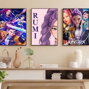 Könnte beinhalten: Drei gerahmte Kunstdrucke mit Illustrationen im Anime-Stil. Der linke Druck zeigt eine dynamische Action-Szene mit Charakteren, die Waffen schwingen. Der mittlere Druck zeigt ein Porträt mit dem Namen "RUMI". Der rechte Druck zeigt Charaktere mit dem Text "HUNTRX".