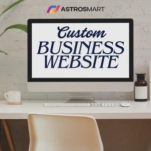 May include: A computer monitor displays the text "Custom BUSINESS WEBSITE" in a stylish, dark blue script. The monitor sits on a white desk with a keyboard, mouse, and a small coffee cup. A brown bottle and a white frame are also on the desk.