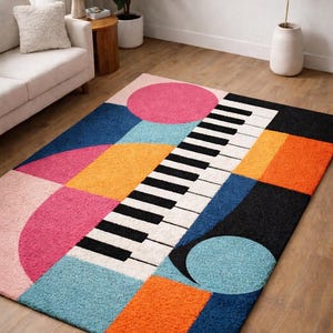 Peut inclure: Un tapis de sol géométrique coloré avec un motif de clavier de piano. Le tapis présente des formes roses, oranges, bleues et noires. Le tapis mesure environ 152 cm de long et 102 cm de large.