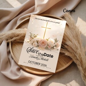 May include: A wedding invitation card with the text "Save the Date" for Kenneth & Michelle, set for October 2026. The design features a gold cross, floral arrangements, and two wedding rings. The card is on a wooden tray with decorative elements.