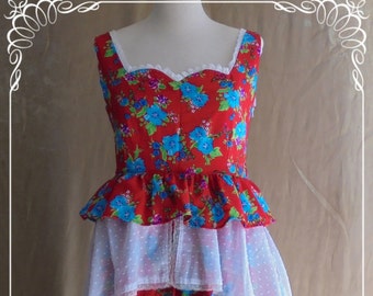 May include: A sleeveless red dress with a floral pattern of blue flowers. The dress features a square neckline, a ruffled peplum, and a tiered skirt with white polka dot and lace accents. The dress is displayed on a mannequin.
