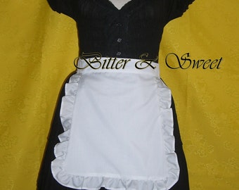 May include: Black dress with a white apron featuring ruffled edges. The dress has a V-neckline and short sleeves. The text "Bitter & Sweet" is displayed across the apron. The background is yellow.