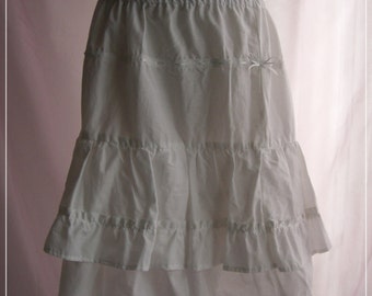 May include: White tiered petticoat skirt with an elastic waistband. The skirt has three layers of ruffled fabric and a small bow detail. The text "Bitter & Sweet" is visible at the bottom of the image.