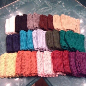 May include: A collection of colorful, knitted wrist warmers in various shades, including white, black, gray, brown, tan, navy, teal, light purple, olive green, dark green, yellow, orange, pink, red, and purple. The wrist warmers are arranged in neat rows.